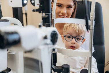 Modern cihazla. Küçük çocuk göz doktorunun dolabını kontrol ediyor..