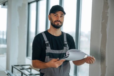 Not defteri kontrol altında. Bir adam bitmemiş bir odayı yeniliyor..