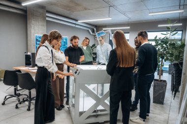 Ofisteki 3D yazıcının etrafında bir grup insan duruyor..