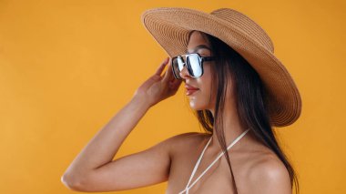 Güneş gözlüğü ve hasır şapkayla. Genç ve güzel bir turist kadın arka plana karşı..