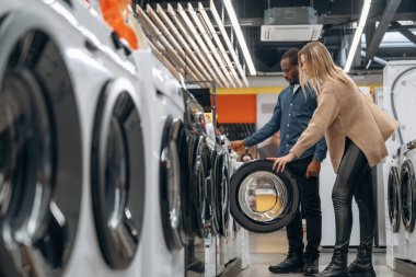 Erkek ve kadın mağazadan çamaşır makinesini seçiyorlar..