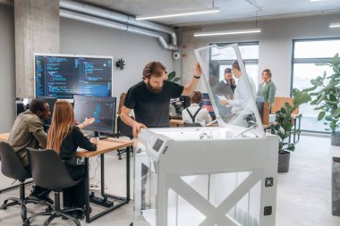 Ofiste 3D yazıcının yanında insanlar var..