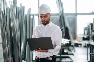 Laptop ellerde. İnsanlar modern fabrikada çalışıyor..