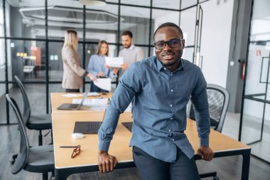 Pozitif siyah adam. Profesyonel işçiler modern ofiste birlikte çalışıyorlar..