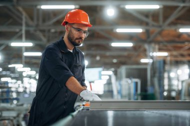 Fabrikanın içinde, ayakta. Adam çalışıyor..