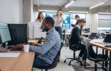 Pozitif siyah adam gülümsüyor. Bir grup ofis çalışanı içeride birlikte..