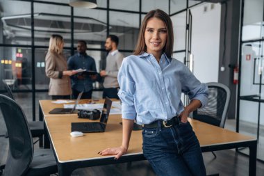 Neşeli kadın ayakta duruyor. Profesyonel işçiler modern ofiste birlikte çalışıyorlar..