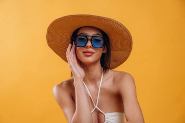 Güneş gözlüğü ve hasır şapkayla. Genç ve güzel bir turist kadın arka plana karşı..