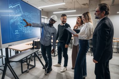 Bina planı ekranda. Bir grup ofis çalışanı içeride birlikte..