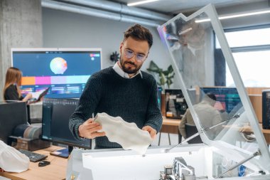 Ayakta. Modern teknoloji. Ofiste 3D yazıcının yanında insanlar var..