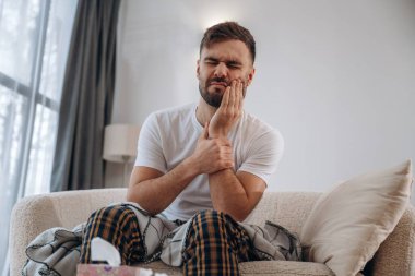 Diş ağrısı, oturma ve acı çekme. Hasta adam evde kendini kötü hissediyor..