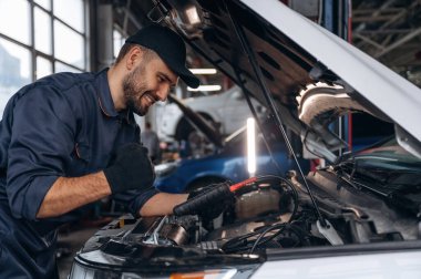 Gülümseyen, neşeli yüz ifadesi. Araba tamirhanesinde çalışan bir tamirci..