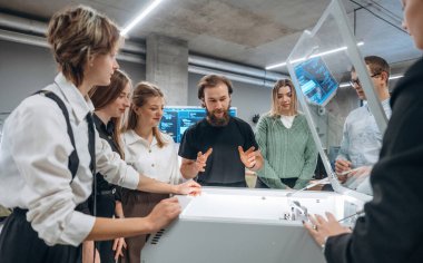 Cihazın nasıl çalıştığını açıklıyorum. Ofiste 3D yazıcının yanında insanlar var..