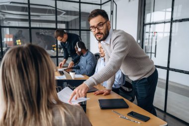 Planı tartışıyoruz. Profesyonel işçiler modern ofiste birlikte çalışıyorlar..