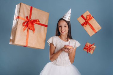 Mutlu yıllar, hediye kutuları, çöreğin üzerindeki mum. Beyaz elbiseli genç kız arka plana karşı..