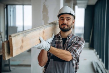 Yürüyen ve kalasları tutan. Bir adam bitmemiş bir odayı yeniliyor..