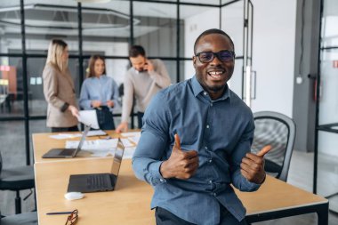 Pozitif siyah adam. Profesyonel işçiler modern ofiste birlikte çalışıyorlar..
