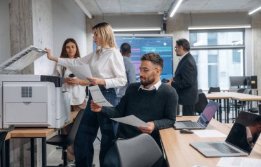 Yazıcı kullanıyor. Bir grup ofis çalışanı içeride birlikte..