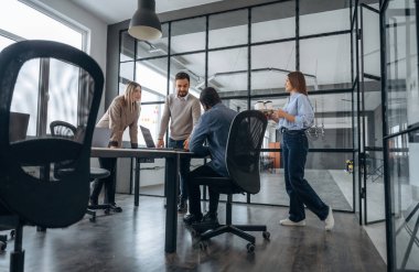 Konuşuyoruz, plan hakkında konuşuyoruz. Profesyonel işçiler modern ofiste birlikte çalışıyorlar..