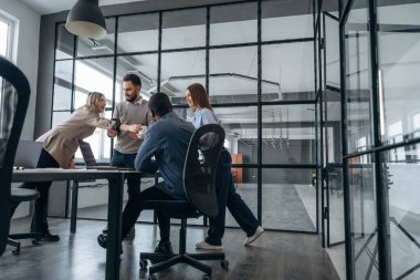 Konuşuyoruz, plan hakkında konuşuyoruz. Profesyonel işçiler modern ofiste birlikte çalışıyorlar..