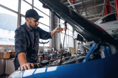 Nakil aracı tamir ediliyor. Araba tamirhanesinde çalışan bir tamirci..