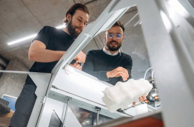 3D yazıcıyı gösteriyor. Ofiste insanlar var..