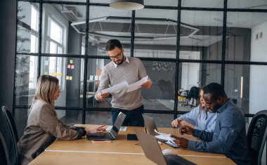 Masanın yanında. Profesyonel işçiler modern ofiste birlikte çalışıyorlar..
