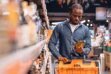 Ellerinde bir şişe sebze yağı. Erkek müşteri süpermarkette..