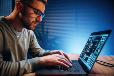 Yan görüş. Erkek programcı içeride dizüstü bilgisayarla çalışıyor..