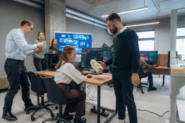 Çalışanlar bir arada. Ofiste 3D yazıcının yanında insanlar var..