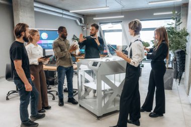 Çalışanlar bir arada. Ofiste 3D yazıcının yanında insanlar var..