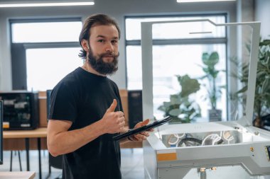 Ayakta, çalışıyor. Adam 3D yazıcıyla ofiste..