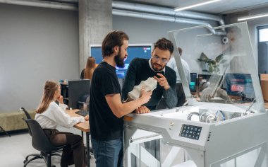 İletişim, bitmiş yazdırılmış nesne. Ofiste 3D yazıcının yanında insanlar var..