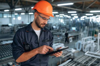 Siyah renkli tablet ellerinde. İnsanlar modern fabrikada çalışıyor..