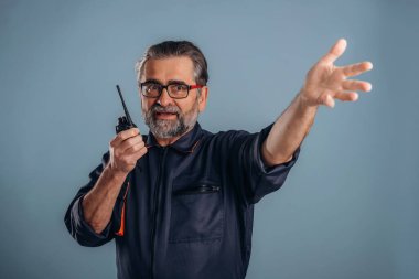 İşçi telsizle konuşuyor. Sunbae stüdyoda arka planda bekliyor..