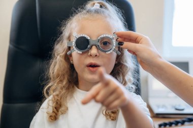 Portre, gözlüklü, ileriye bakıyor. Göz doktoru kliniğinde doktorla küçük bir kız..