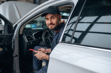 Otomobilde oturmak. Araba tamirhanesinde çalışan bir tamirci..
