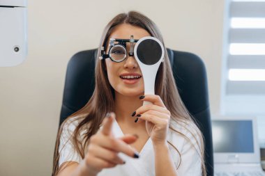 Genç kadın göz doktorunun dolabında görüşünü kontrol ediyor..