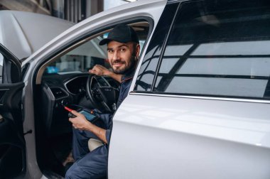 Otomobilde oturmak. Araba tamirhanesinde çalışan bir tamirci..