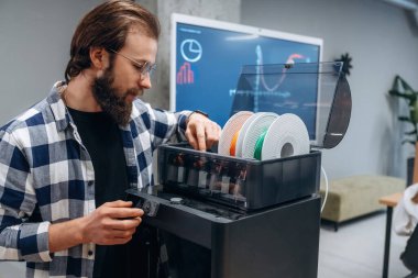 3D yazıcı için plastik yükleniyor. İnsan modern ofiste, tek kişidir..