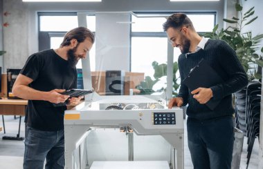 İşbirliği ve iletişim kavramı. Ofiste 3D yazıcının yanında insanlar var..