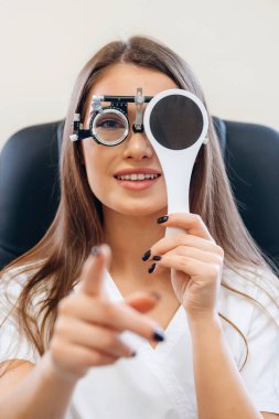 Genç kadın göz doktorunun dolabında görüşünü kontrol ediyor..