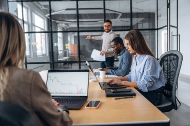 Kablosuz cihazlar, masadaki dizüstü bilgisayarlar. Profesyonel işçiler modern ofiste birlikte çalışıyorlar..