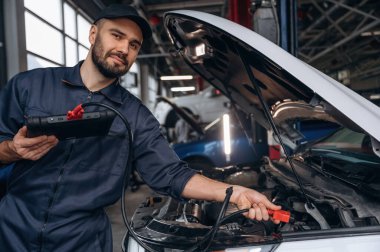 Tableti bağlamak için kablo. Araba tamirhanesinde çalışan bir tamirci..