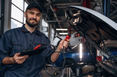 Tableti bağlamak için kablo. Araba tamirhanesinde çalışan bir tamirci..