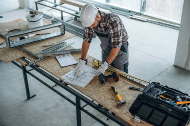 Üst manzara, masanın yanında duruyor. Bir adam bitmemiş bir odayı yeniliyor..