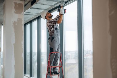 Pencerelerin yanında. Bir adam bitmemiş bir odayı yeniliyor..