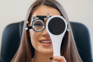 Genç kadın göz doktorunun dolabında görüşünü kontrol ediyor..