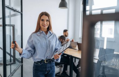 Kadın ayakta duruyor. Profesyonel işçiler modern ofiste birlikte çalışıyorlar..