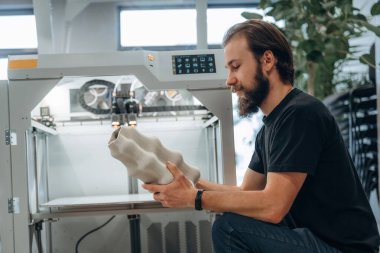 Ürün hazır. Adam 3D yazıcıyla ofiste..